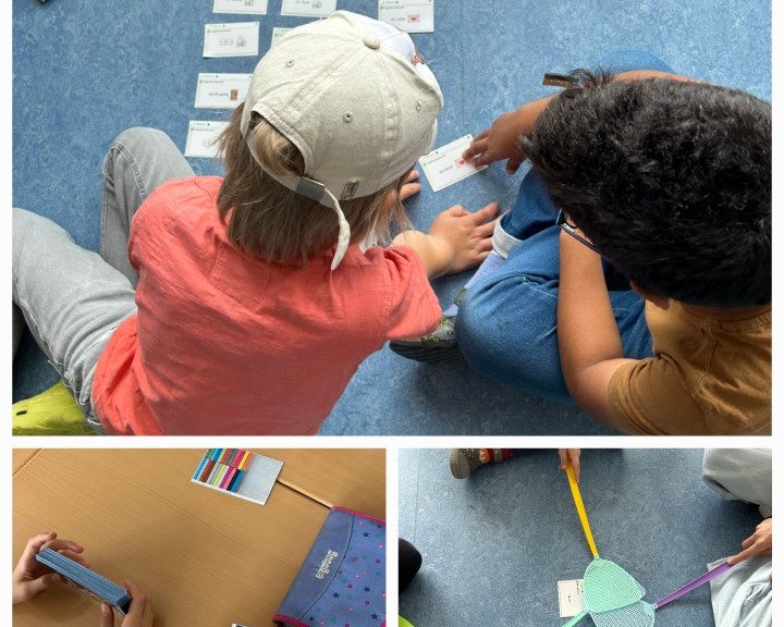 Kinder sitzen auf dem Boden und bearbeiten gemeinsam eine Lernaufgabe