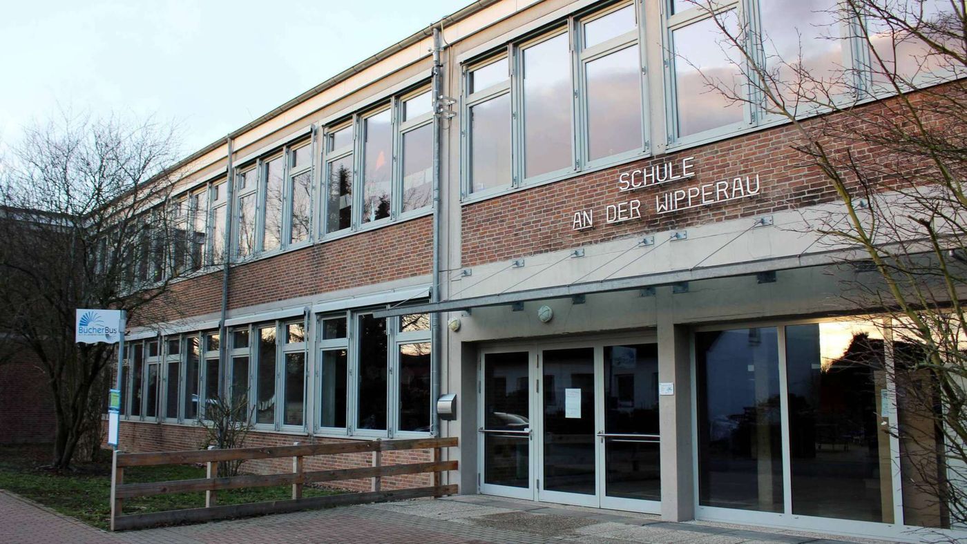 Das Schulgebäude der Schule an der Wipperau: ein zweistöckiger Backsteinbau mit großen Fenstern und dem Schriftzug Schule an der Wipperau über dem Eingang.